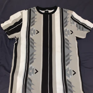 River Island Grå Mönstrad t-shirt (Small) - En mönstrad t shirt från river island i storlek S säljes för 80kr. Väldigt bra skick.