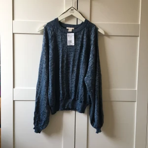  - Glittrig tröja, turkos med silvertrådar. Ärmarna är slitsade, se bild två. Av viskos, polyester, silke. Nypris 499kr, aldrig använd!