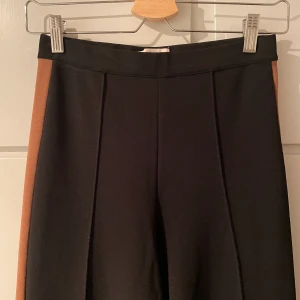 Byxor HM Trend, 36 - Byxor från HM Trend, svarta med brun tant längs med sidan. Sparsamt använda, mycket fint skick. Storlek 36.