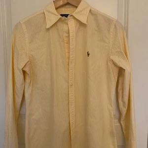 Ralph Lauren skjorta  - Gul och vitrandig Ralph lauren skjorta i storlek 11 (motsvarar s). Den är även lite figursydd. Säljer skjortan då jag inte använder den. Den är som ny, inget slitage och knappt använd. Pris går att diskutera. Om du har frågor eller vill ha fler bilder är det bara att höra av sig. ☺️ (köparen står för frakten). 