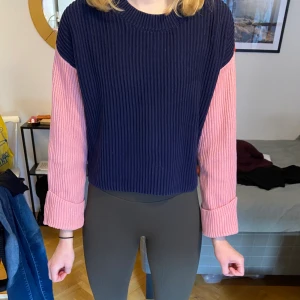 Flerfärgad stickad tröja  - En fin stickad tröja med färgerna marinblå, rosa och röd. Tröjan har ballongarmar och uppvikningar som sitter fast. Köpt på Åhléns. Väl använd men i mycket bra skick 