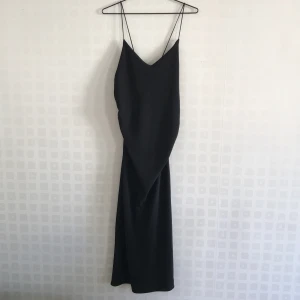 Elegant coctailklänning - Elegant klänning som kan stylas både med eller utan en t-shirt under. Klänningen är vadlång med en slits. Fin ryggskärning. Köparen står för frakten.