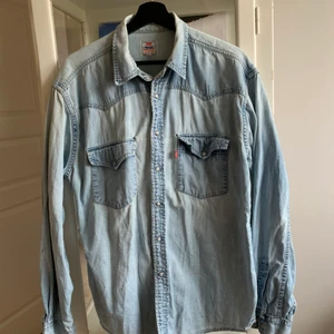 Levis jeans skjorta - Oversized jeans skjorta från Levis. Har två små hål över vardera ficka. Kan mötas upp i Fruängen, annars tillkommer fraktkostnaden! Storlek L