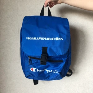 Champion Ryggsäck  - Kornblå ryggsäck från Champion. Rymlig med många fack. Resår i öppningen.