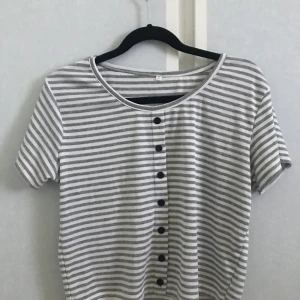 Grå randig tröja - Passformen är normal och den slutar lite över naveln på mig som är ca 170 cm. Materialet är väldigt stretchigt den skulle förmodligen passa någon från strl XS-M kanske L. Beror såklart på hur man vill att den ska sitta. Knapparna går inte att öppna.