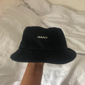 Fiskehatt från Gant, liten damstorlek  - Snygg fiskehatt från Gant i fint skick, vad jag vet är den aldrig använd. Står gant Woman i, men passar såklart killar med. Svart typ jeans tyg. Obs den är ganska liten! Omkretsen på insidan är 54 cm, så passar nog dig med lite mindre huvud. +25kr i frakt
