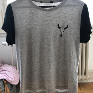 Grå t-shirt med en tjur på - Vet ej märket. En grå t-shirt med svarta ärmar, är i bra skick i stl S