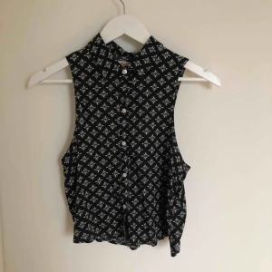  - Fin blus. Aldrig använd. Toppenskick och bra kvalité. På ryggen är det en fin detalj med en cut out. Svart med vita mönster. Lite kortare i modellen. Frakt tillkommer.