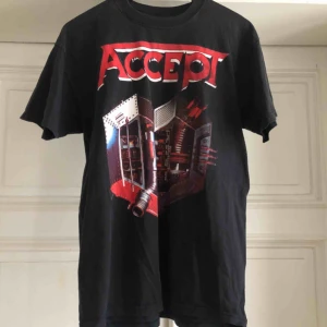  - Accept bandtröja. Kan hämtas i Uppsala eller skickas mot fraktkostnad. Snyggt urtvättad. Hål på nedre delen av framsidan som bara är snyggt och mer heavy metal 