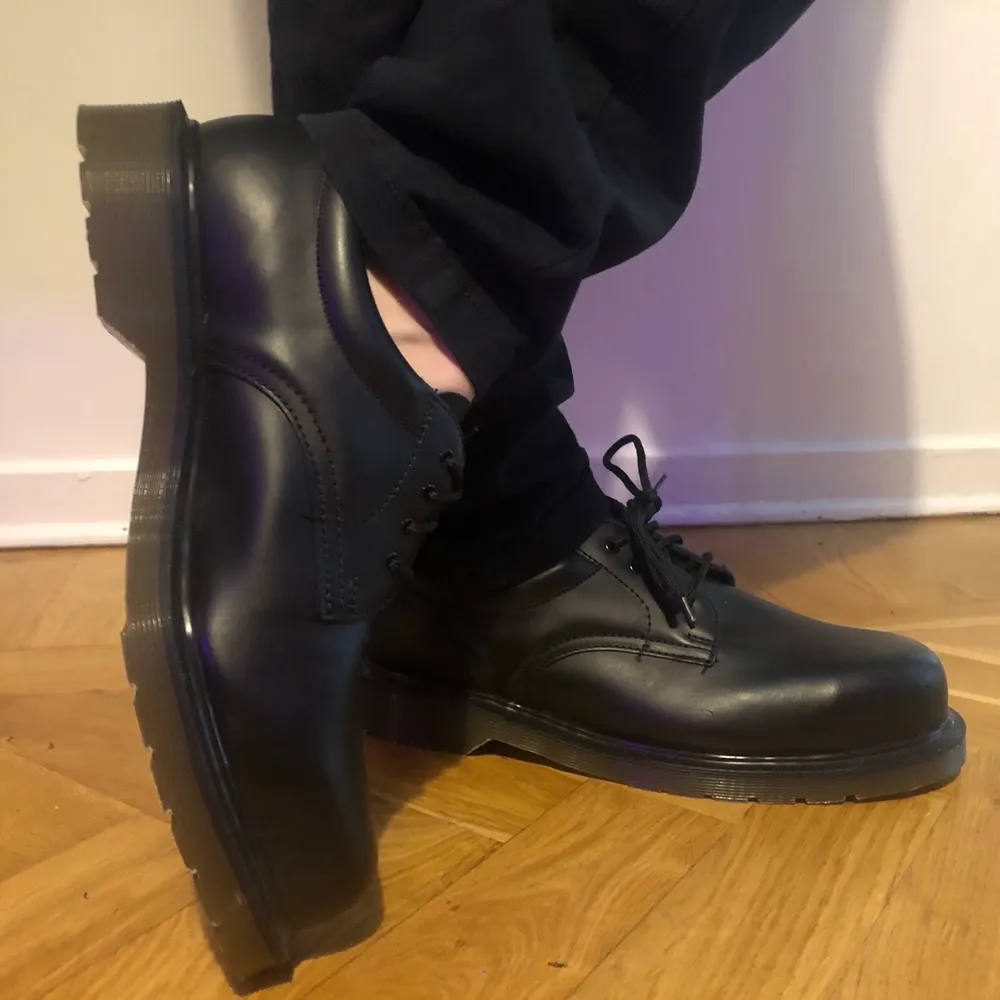 Oanvända Dr.Martens. Kan skickas, du betalar frakt. Denna modellen liknar den klassiska modellen från Dr.Marten. MEN detta är en industrimodell (kolla snörningen) med stålhätta. En säkerhetssko.  Modell 2215 Det jag kan veta är att Dessa skönheter är äldre än -06 då det köptes upp ett litet lager från ett konkursbolag.  De har fått stå i sin original kartong och lagrats.  New Vtg Dr Doc Martens 2215 Black Steel Toe Safety Shoes   Made in England ~ 2215 Black ~ Steel Toe ~ Slip Resistant ~. Skor.