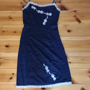 Blå slipdress  - En blå slipdress i meshtyg med vit spets på kanten och spetsdekorationer.