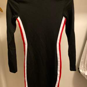 En svart, kort klänning med röd och vit linje på sidorna