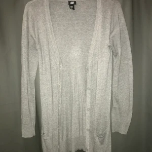 Grå kofta - Grå tunnstickad kofta av längre modell, strl 134/140 men passar även XS. Köpare står för frakt