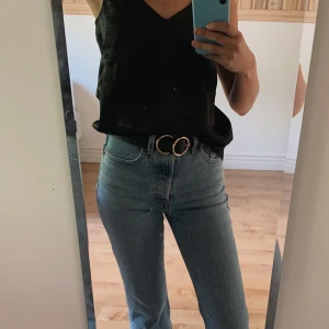 Svart skärp i läderimitation med gulddet - Sparsamt använt. Priset är inkl frakt.