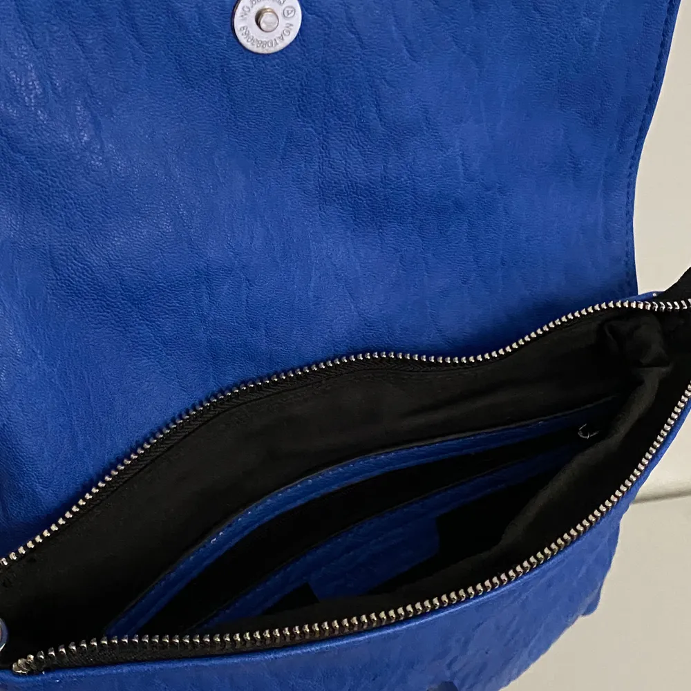 En blå väska med detaljer. Väskor.