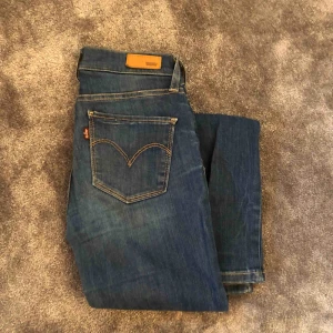  - Blå tighta stretchiga jeans från Levi’s. Storlekslappen finns inte kvar men de passar mig som normalt har 26-27, de är stretchiga. Använda en del, därför lite slitna men inget som ”förstör. NYPRIS: 1199 kr. 