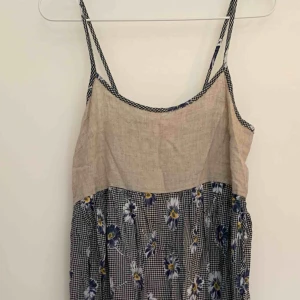  - Halvlång klänning med smala axelband och band som kan knytas runt midjan. Blommig kjol med hampaliknande tyg upptill.   Köparen står för porto. 