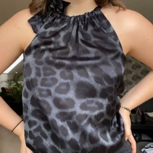 Silkestopp från Neo Noir i leopardmönster - Leopardmönstrad silkestopp i halterneck-modell med justerbart band vid halsen. Fin svart-blå färg som både går att klä upp och ner! Endast använd 1 gång så väldigt bra skick! Köpt för 600kr och säljes för 150kr exklusive frakt