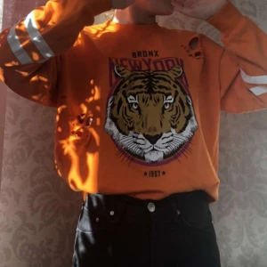 Orange sweatshirt strl S - Häftig sweatshirt med tryck och slitningar från Gina tricot. Använd men i fint skick. Trycket på baksidan av ärmarna är dock lite slitet, inget man tänker på men kan skicka en närmare bild på det vid intresse. Köparen står för frakt🧡