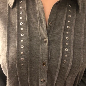 Grå blus med nitar - Häftig grå blus som är croppad med coola nitar på framsidan! Tjejen som har på sig tröjan har storlek S men passar upp till L beroende på hur man vill att den ska sitta. Frakt tillkommer❤️❤️