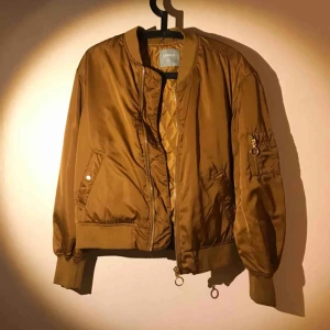  - Lejongul bomberjacka, sidenkänsla, dragkedjor i gulmetall, Lindex, obetydligt använd, fint skick.