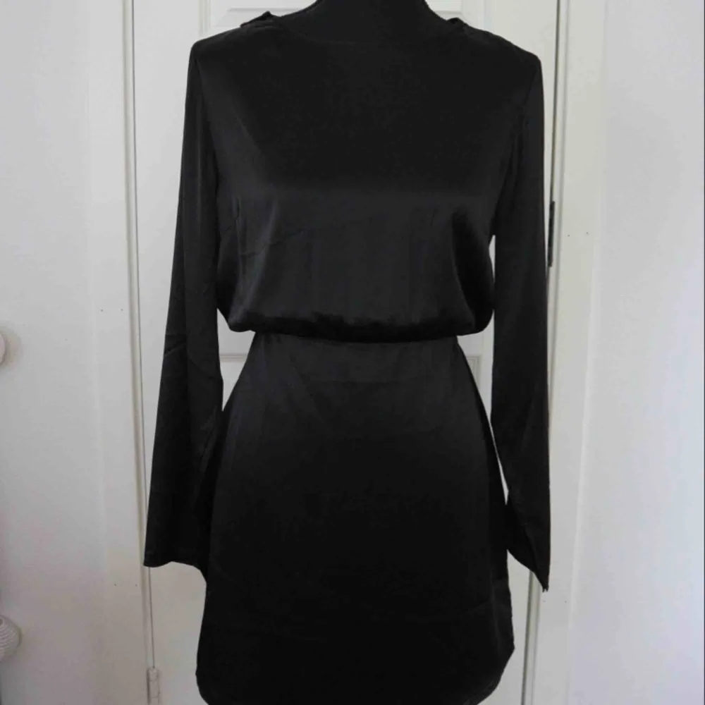 Säljer en svart klänning i ett siden material med öppning i ryggen. Klänningen är i nytt skick! Storlek: 40 . Klänningar.