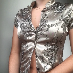 Festlig topp - Blus med blommigt motiv och glansigt tyg. Stängs med knappar hela vägen, däremot är knapphålen lite slitna och fransiga. Skriv vid funderingar✨😊