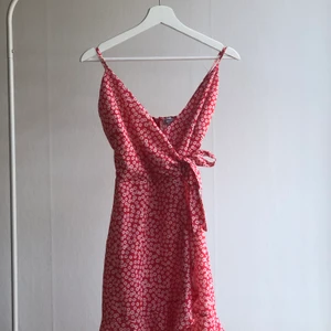 Rödblommig klänning från Chiquelle, strl XS - En jättefin sommarklänning från chiquelle. Använd två gånger. Säljer för att jag har en annan nästan identisk klänning. Storleken är XS och den går ner ungefär till mitten av låren på mig, är 164cm lång. Går att knyta åt i midjan vilket ger en väldigt fin passform. Orginalpris är 499. Köparen står för frakt🌺 