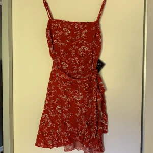 Röd sommarklänning  - En röd sommarklänning i strl 36. Jätte fin klänning som är omlott, med knytning på sidan. Dragkedja på baksidan. Oanvänd. Du betalar frakten💕