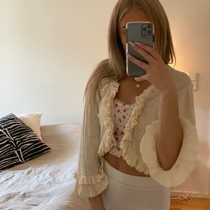 Cremevit kofta med volanger - Världens sötaste kofta från Flash i storlek M men skulle säga att den passar mindre också beroende på hur man vill att den ska sitta. Har ett litet hål i ena innerärmen men det är inget som syns. Den är så söt! Buda från 150kr, frakt tillkommer 🤎🤍