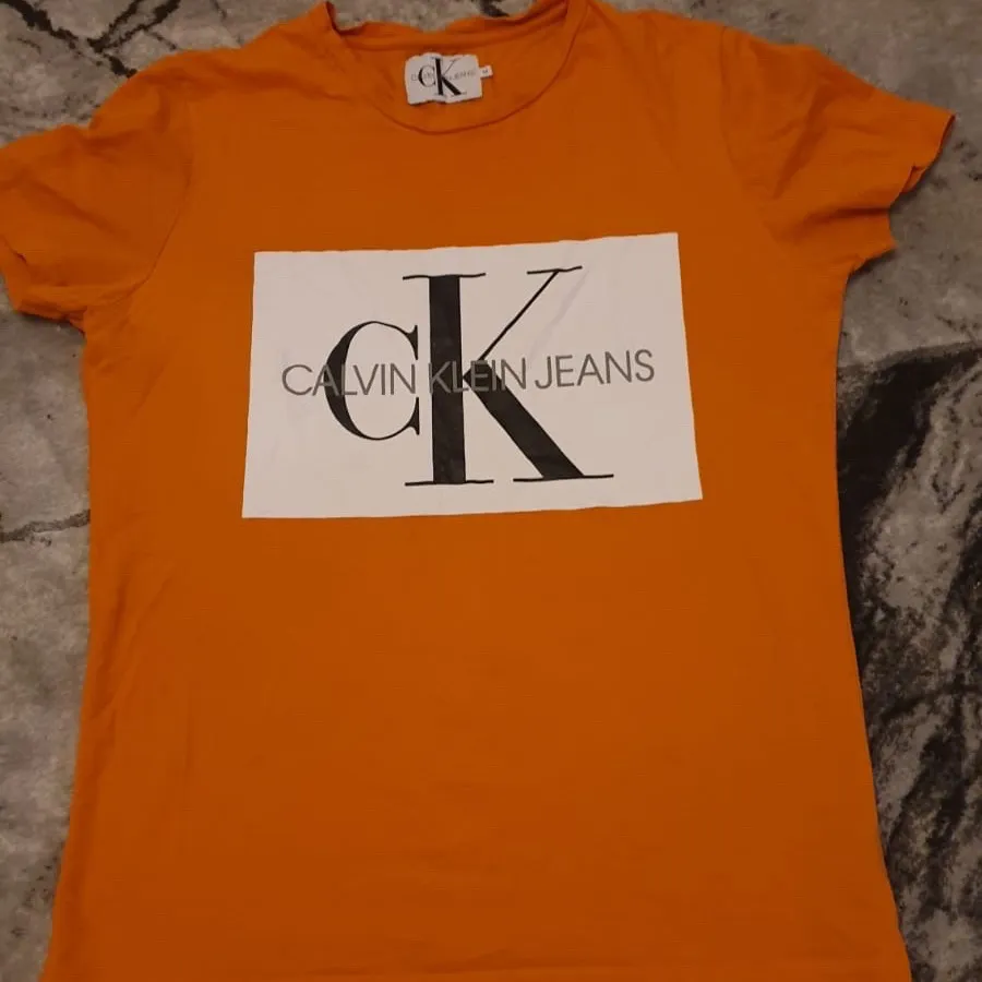 FRI FRAKT                                                                   En smuts orange färgad T-shirt men Calvin Klein tryck på. Använt 1-2 gånger. •Nyskick  • Strl M men passar bra som S (ganska liten i storleken) • Säljer på grund av att jag beställde den och den var för liten eftersom den är liten i storleken och valt att sälja den istället för att skicka tillbaks den.  • Ny pris 399kr men säljer för 200kr • Priset kan diskuteras • Säg till om ni vill ha en bild om hur den sitter på  . T-shirts.