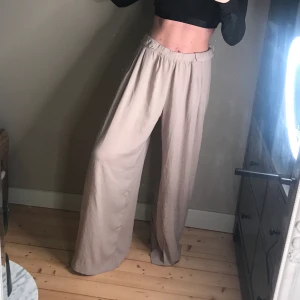 Beigea vida byxor från Zara - Superhärliga vida byxor från Zara. Resår i midjan. Längre i modellen så passar bäst om du är lite längre alt. med ett par klackar (som jag har burit dem). Passar S-M beroende på hur du vill att de ska sitta 🌸 kan även posta, pris ex. frakt.