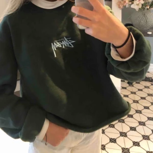  - Sweatshirt i mörkgrönt med ljusblå Stüssy logga, köpt på Hollywood, plagget är i fint skick. Herrmodell men funkar såklart för alla!