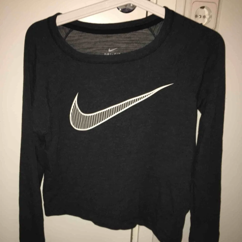 Grå Nike sweater som är snett croppad nertill. Tröjor & Koftor.