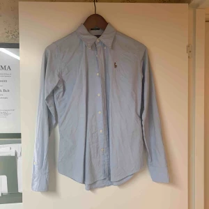  - Ljusblå långärmad skjorta från Ralph Lauren i slim fit modell. Använd ett fåtal gånger. Mycket fint skick. 
