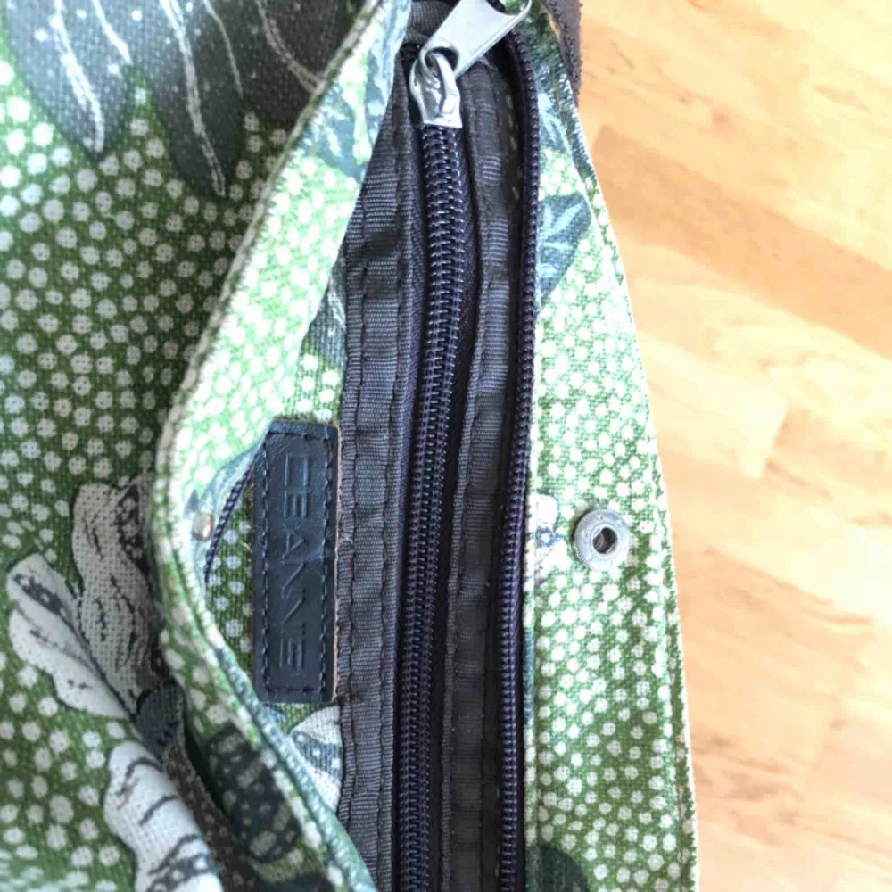 Superfin tygväska från märket Ceannis i grönmönstrat tyg. Brett axelband som kan justeras i längd. Finns tre innerfack och kan stängas med både dragkedja och knapp. Säljs för att den förtjänar att användas mer än jag gör :). Väskor.