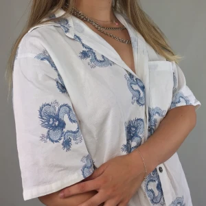 Dragon Shirt - A super dope button up t-shirt with blue dragons all over. From Razia Fashion, labeled as an L. The shirt have two small slits on each side. Reminds of something Billie Eilish would wear. No return nor refund. Free shipping everywhere in Sweden.