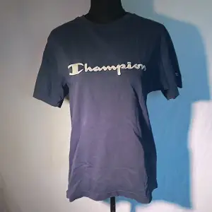 Mörkblå champion t-shirt, litet minihål nere på ryggen som syns på andra bilden