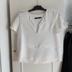 Vit volang blus - Vit blus från zara, fin i tyget med volanger och öppning fram vid bysten. Storlek S