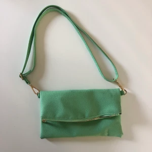 Pastellgrön axelväska - Liten väska med justerbart band. Köpt second hand men aldrig kommit till användning för min del.