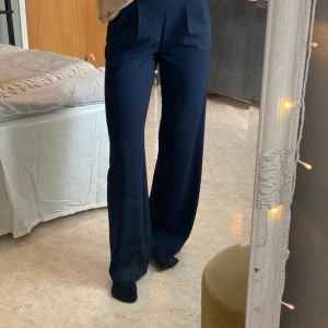 Kostymbyxa - Snygg marinblå kostymbyxa. Byxan har en rak och vid passform med fint fall, är något högre i midjan. Endast använda en gång. Märke: STOCKH LM, storlek: 34. ordinarie pris: 699kr. Buda i kommentarerna eller skriv till mig privat! Frakt tillkommer om mötas inte är möjligt!   Startbud: 300kr