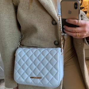 Blå axelväska - En blå axelväska/handväska från Miinto köpt i Polen. Oanvänd iprincip, fin ljusblå färg, kvalité även om det inte är ett dyrt märke! 