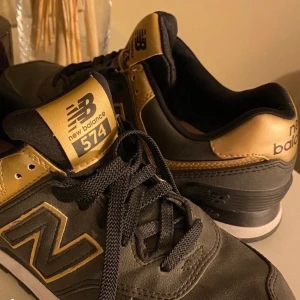 Oanvända new balance  - Helt oanvända new balance 574 i färgen grå/svart och guld. Köptes för 1000 kr.