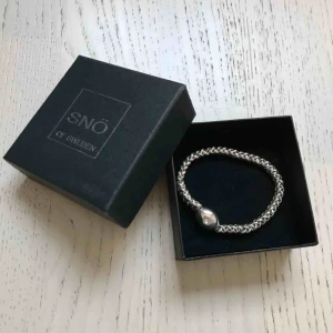  - Helt nytt armband från SNÖ, aldrig använt. Säljes i sin orginalförpackning. Tex. En perfekt present!   Armbandet är elastiskt så flexibel storlek/passform.  Se bilder för mer detaljer & skick, zooma gärna & swipa för fler bilder.