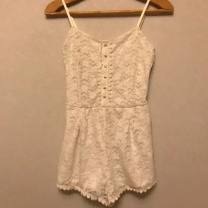  - Jättesöt vit byxdress från H&M. Spets med tunt foder. Storlek 36 men passar en 34. Fin detalj med öppningen i ryggen. Frakt tillkommer.