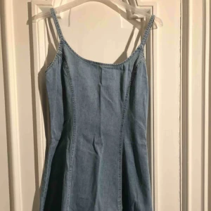  - Kort jeansklänning i figursydd modell med klockad kjol. 