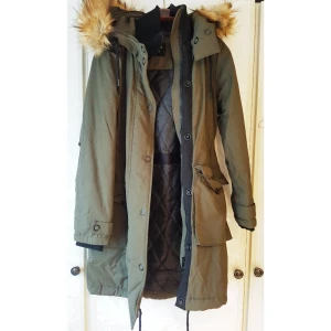  - Vinterjacka i mörkgrönt från Lindex. Nypris 700kr. Aldrig använd. Mudd i krage och ärmslut. Dragsko i midjan och nederkant. Fuskpäls i fin, mjuk kvalité. 