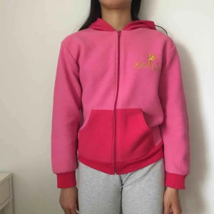  - En rosa huvtröja med tryck på både bak o framsida, flismatrial.