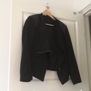  - Snygg kavaj i svart fintyg, skinndetaljer och kedja. Stretch