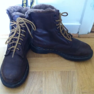  - Bruna höga vinterkängor från Dr Martens. Använda en vinter, några små saltfläckar vid sulan. Finns även svarta skosnören till dem.   